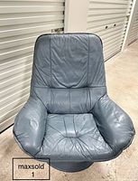 Full front view of vintage grey leather swivel armchair showing patchwork design and wear on leather.