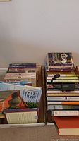 Photo showing two boxes filled with assorted books, titles partially visible, arranged vertically and stacked