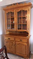 Photo of two-piece oak buffet and hutch showing glass doors, brass pulls, wood finish and overall condition