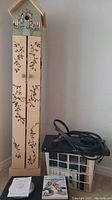 Photo of decorative wooden birdhouse-style CD tower with floral vine painting, showing full height and top with birdhouse opening.