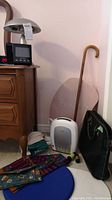 Photo showing various wellness and office items on the floor including hand massager, aquafit board, lap desk, cane, small office bag.