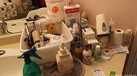 Overview of hair appliances, soap dispensers, paper cups and dispenser, bandages, and tape on bathroom counter.