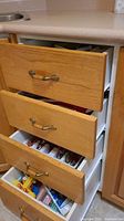 Wooden drawers containing multiple kitchen knives of different sizes and handles.