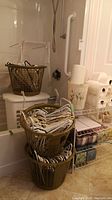 Laundry baskets stacked in bathroom containing hangers, tub in background.