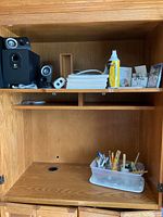 Photo of wooden cabinet shelf showing Logitech Z313 stereo speakers and subwoofer on the top shelf with wired speakers, new air duster can, binder paper pads, DVD case, and multiple floppy disks.