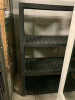 Full view of shelving unit from the front showing the four shelves and frame constructed of black plastic.