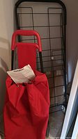 Photo showing the red Pack Mate cloth bag shopping cart alongside a larger black wire folding shopping cart.