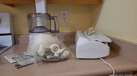 Wide shot showing the food processor with attachments and the FoodSaver vacuum sealer on a kitchen counter.