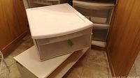 Plastic Sterilite storage drawer on top of a laminate shoe rack, drawer slightly pulled out