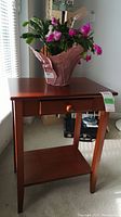 Wood rectangular end table with drawer and lower shelf, reddish-brown finish, with minor surface scuffs visible.
