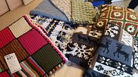 View showing multiple crocheted blankets and cushions with various colors and patterns, along with two polar fleece blankets with winter themes.