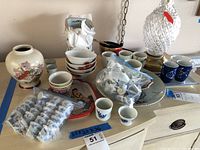 Full view of all cups, bowls, plates and a large clear glass diamond-cut vase.