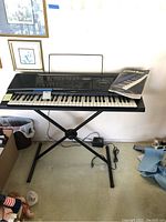 Full view of Casio KT-90G keyboard on X-metal stand with power adapter near wall.