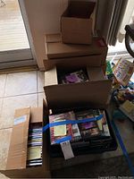Photo showing multiple cardboard boxes and a plastic bin containing assorted DVDs.