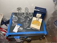 Top view showing seven decorative stoppered clear glass bottles of various shapes including a yellow-tinted fragrance bottle in box.
