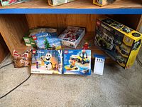 Full view of seven Lego sets on floor including Frozen Olaf, Lego City Beach Rescue ATV, Avengers, and Lego Creator 3-in-1 box leaning on shelf.
