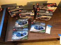 Seven Lego Speed Champions sets displayed on tabletop, including boxed and polybag sealed sets mostly featuring McLaren cars.