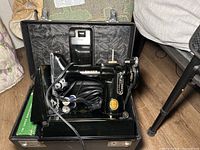Singer sewing machine inside black carrying case with cord and attachments