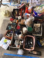 Overview of lots including Simple Human soap dispenser boxes, hand tools, various hardware, electrical cords, and small containers with parts.