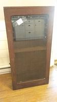Front view of antique wooden jelly cabinet with glass door and visible shelf inside