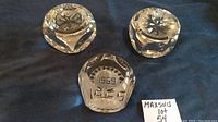 Photo showing three clear crystal paper weights on dark surface; one features etched year '1969' and decorative cuts
