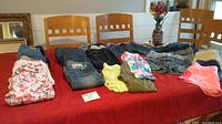 Full view of 22 pairs of girls jeans, shorts and leggings laid out on table.