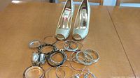 Silver glitter open-toe pumps size 8 with several silver and black/brown bracelets and watches on a wooden table.