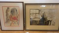 Two framed art prints on floor, one with stylized woman and child figure, other with woman seated by window