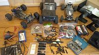 Overview of four RC vehicle chassis and assorted parts laid out on floor
