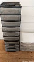 Tall black frame plastic storage unit with 8 clear drawers and smaller white unit with 3 drawers shown side by side