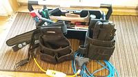 Photo of tool belt, toolbox, and various hand tools arranged on floor