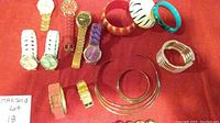 Full view of lot showing watches, bangles, cuff bracelets, necklaces, and beaded bracelets on red background