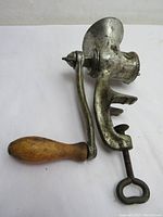 Full view of the cast iron meat grinder showing wooden handle and clamp.