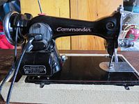 Full side view of vintage black Commander sewing machine showing motor, controls, and sewing area.
