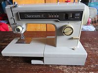 Side view of gray Kenmore 10 sewing machine showing overall machine shape, base, and control knobs.