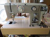 Side view of vintage Kenmore sewing machine in beige and brown on a brown base.