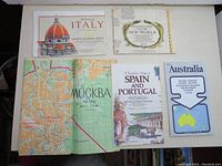 Five vintage maps laid out on a flat surface showing various world regions.