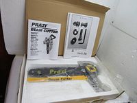 Photo of the Prazi Beam Cutter saw attachment laid on open box with user manual and parts sheet showing missing bolts.