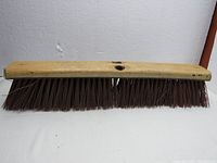 Shop broom head with wooden block and hard brush bristles, showing front view and top view with two handle attachment holes.