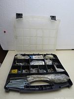 Overview of the open plastic organizer box with 14 compartments filled with assorted screws, bolts, nuts, washers, brackets, and other hardware items.