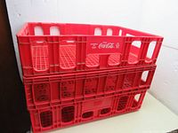 Three red Coca-Cola plastic crates stacked showing size and condition.