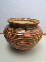 Front and side view of the vintage flower pot showing its bulbous shape and glossy brown and red striped glaze.