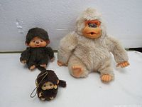 Photo of three Monchichi dolls: smallest and medium Sekiguchi dolls and largest Ganzbros doll seated together