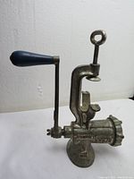 Side view of the vintage SPONGE London No. 5 meat grinder showing the blue wooden handle, clamp screw, and metal body.