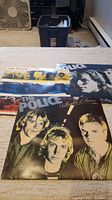 Three vinyl records by The Police laid out showing front covers with band member imagery and color themes.