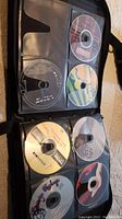 Photo showing a binder page with 8 compact discs featuring varied artwork and labels including album titles and artist names.