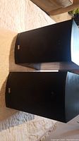 Front view of two black PSB Alpha B bookshelf speakers with fabric grilles.