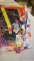 Six women's bike jerseys still sealed in original plastic bags showing vibrant black, red, yellow, and blue colors with visible tags and labels.