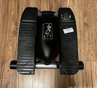 Top view of the LTT stepper exercise machine showing black textured foot pedals and small display panel on right side with step icon and settings.