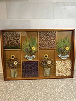 Full front view of rectangular wooden serving tray with glass top containing various dried floral sections arranged in decorative patterns inside.